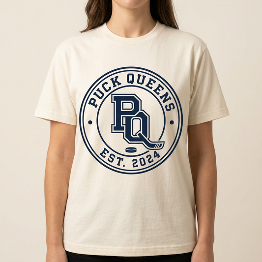 The Crest Tee in cream, navy circular Puck Queens crest printed across the chest