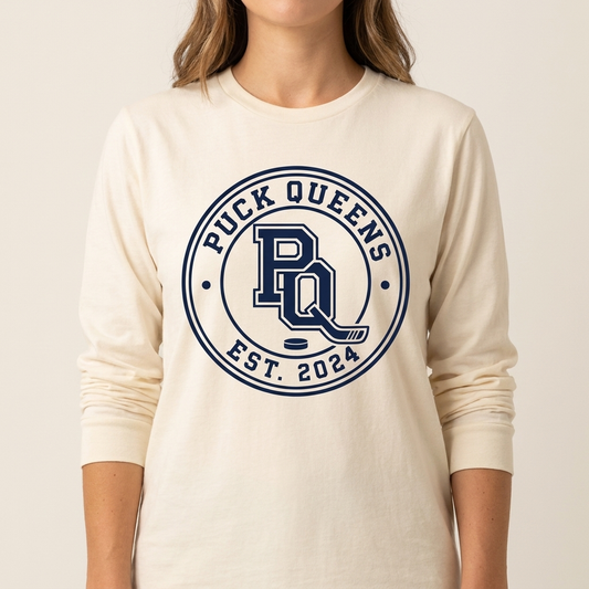 Cream long sleeve tee with the navy Puck Queens circular crest on the chest